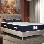 Un matelas avec mousse à mémoire de forme visco aérial et tête de lit en velours gris effet texturé.